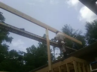 Carpenter setting a ridge beam over a new addition frame — Ice Dam Removal by Roofing Brothers in Erie