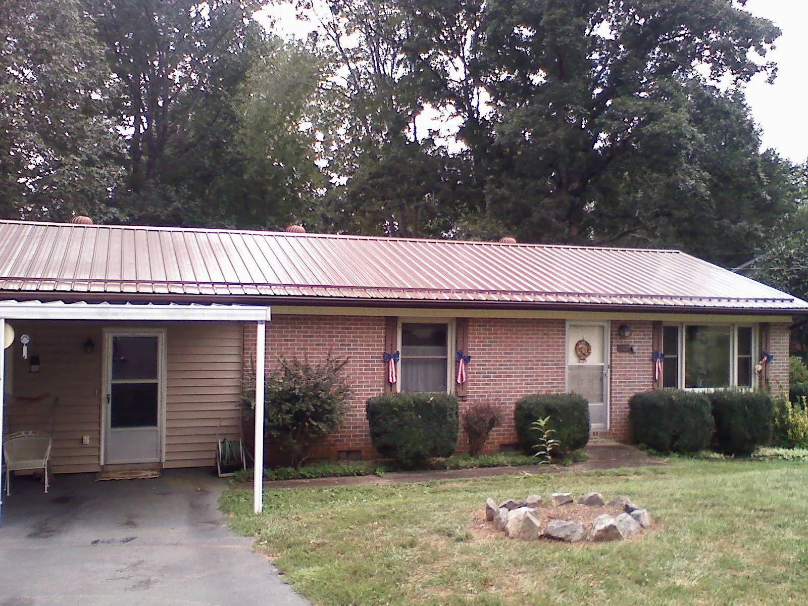 Bronze metal roof and carport on a brick ranch home — Roof Repair work by our crew in Erie