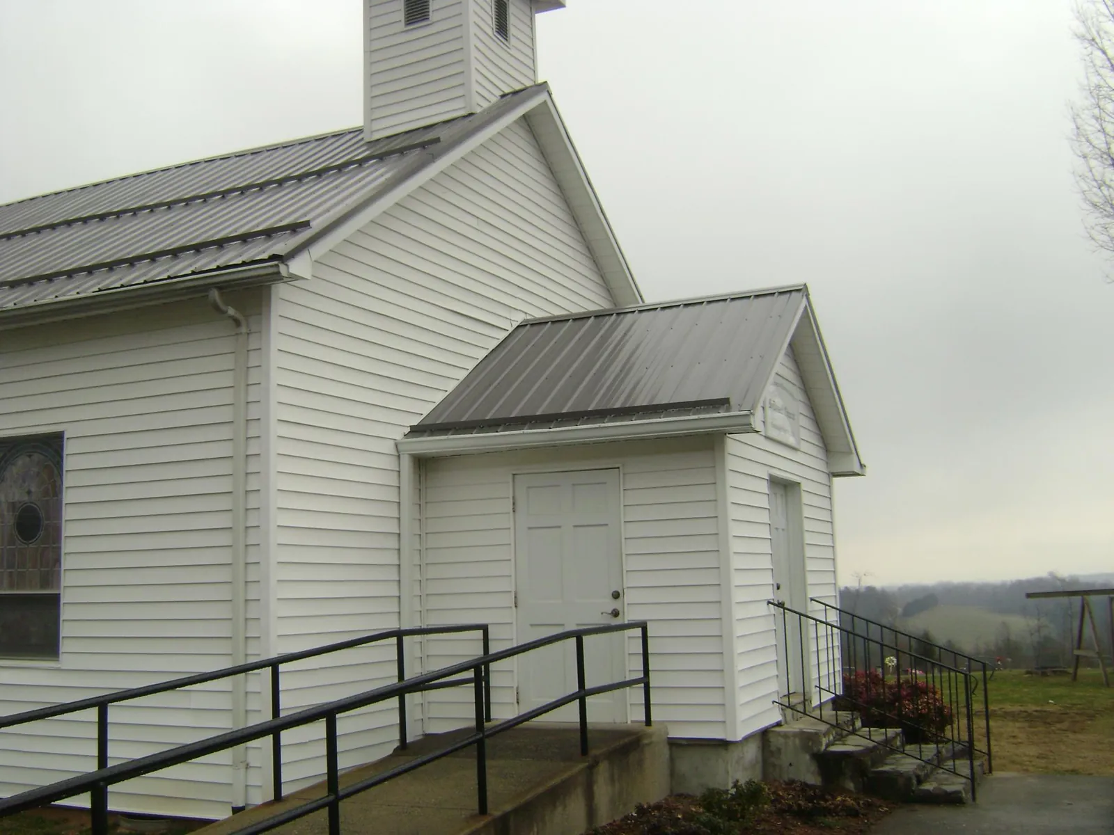 Gray metal roof on a white clapboard church with a steeple in Erie